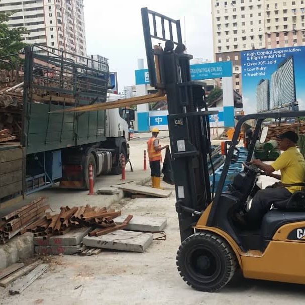 An M&C CAT forklift operating on a worksite in Penang beside a crane lorry